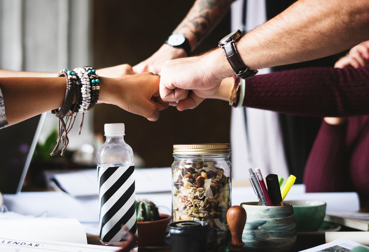 Group of employees fist bumping over desk in an office