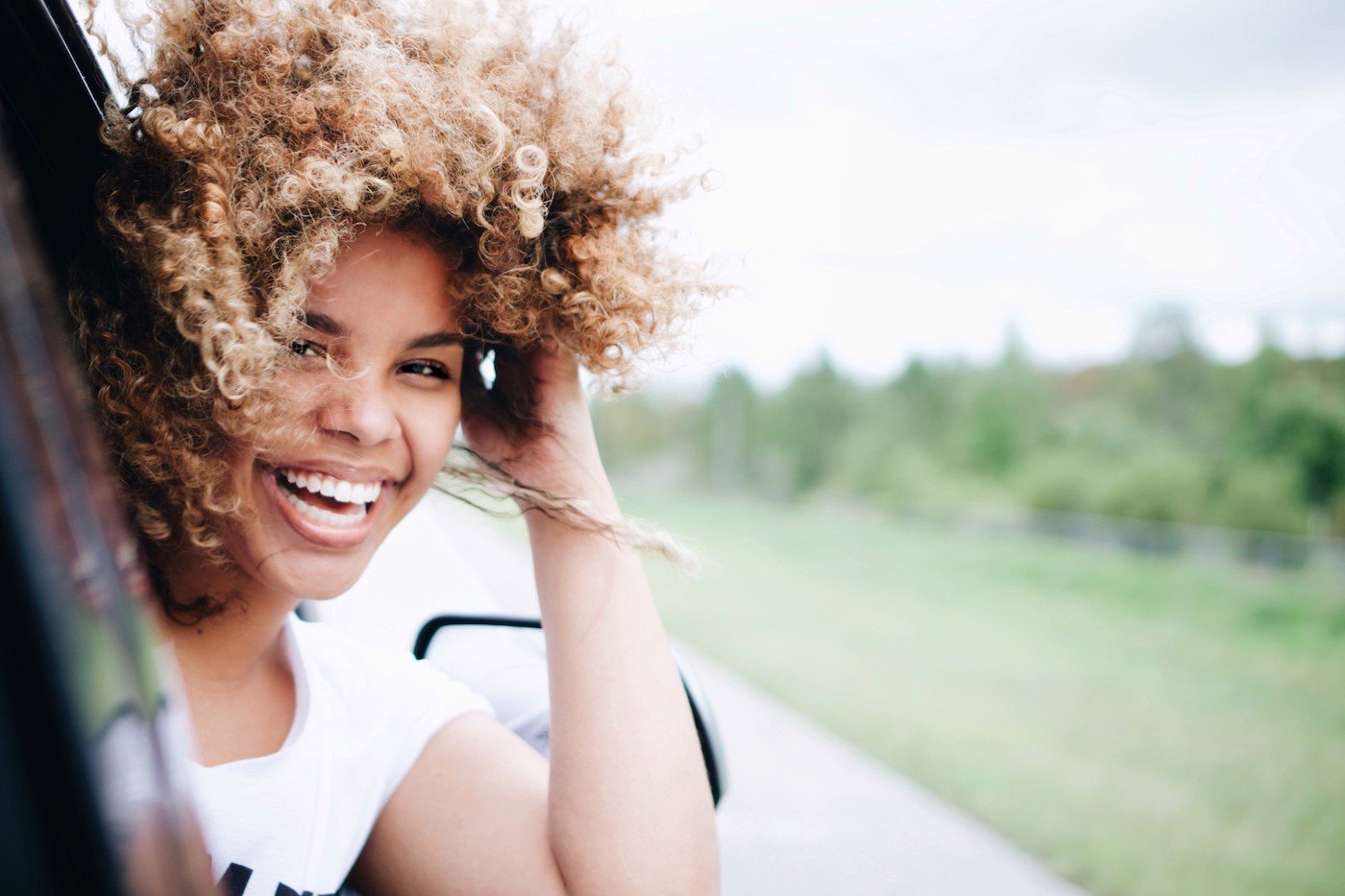 happy woman with her head out of a car window