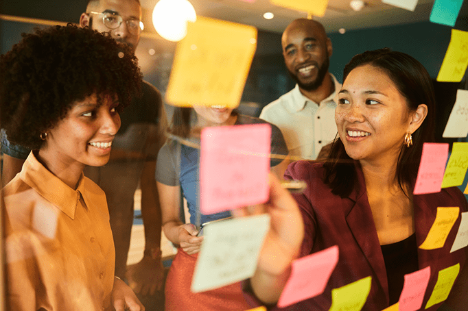 Neurodiverse businesspeople smiling during a brainstorming session with adhesive notes