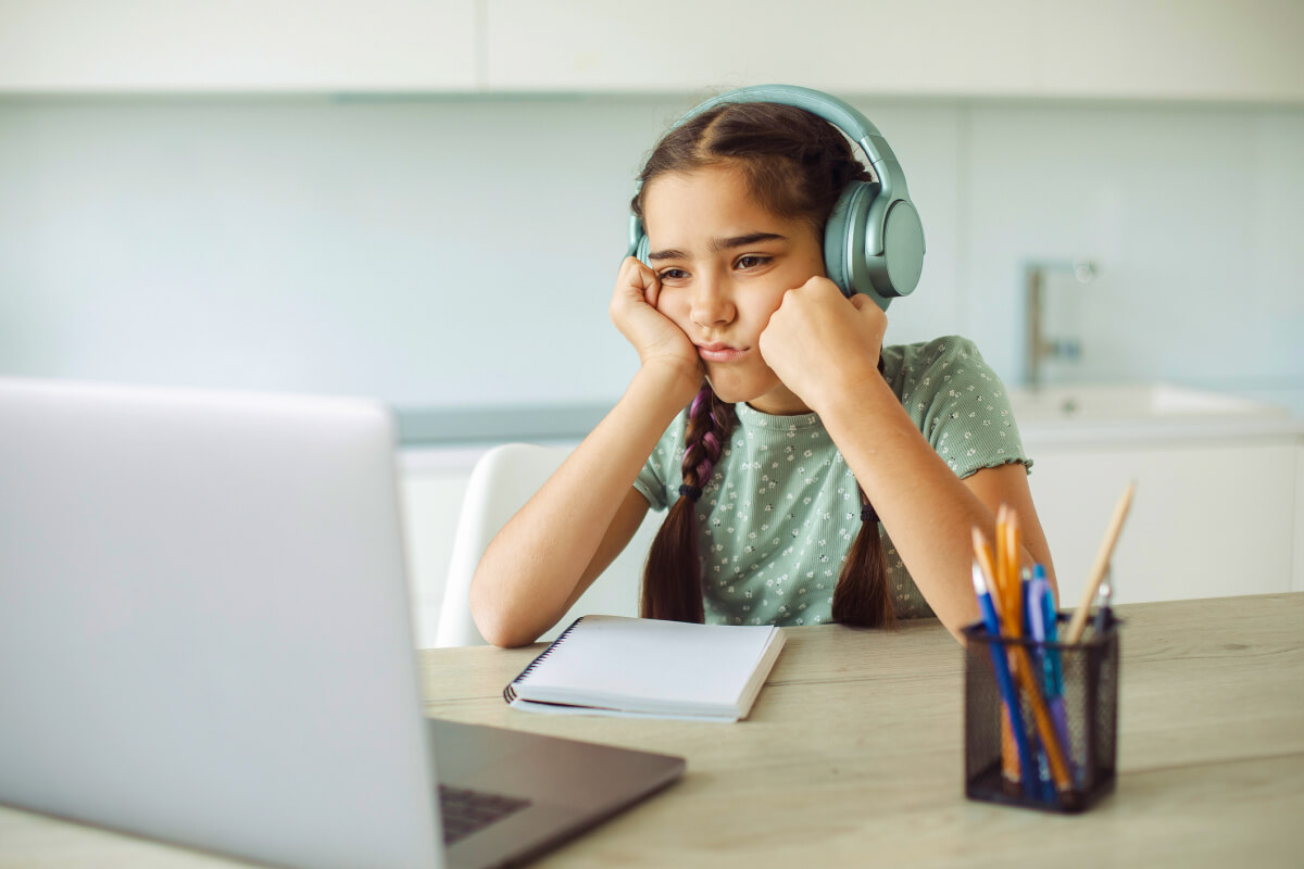 schoolgirl at home on laptop bored studying during summer