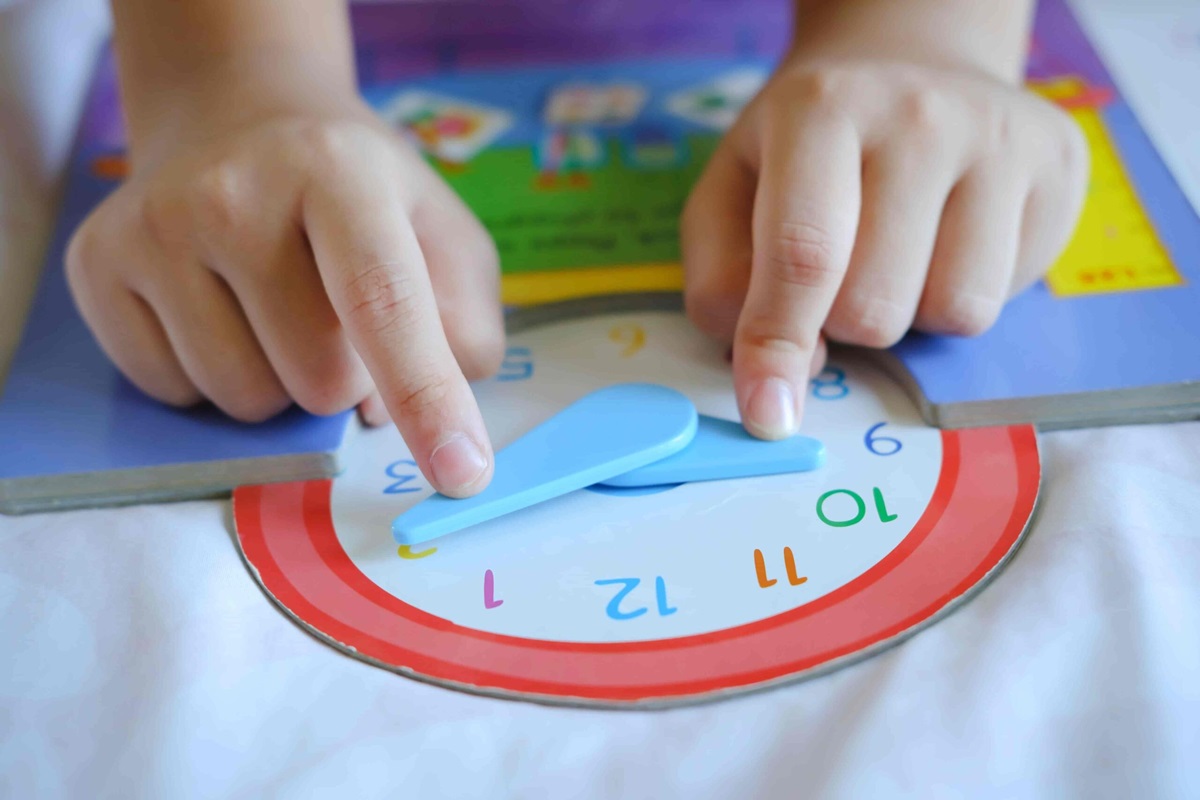 kid playing with analog clock in book