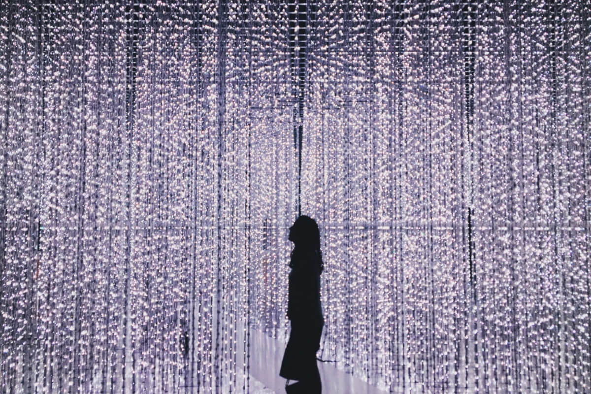 woman standing in museum with beads of lights hanging from ceiling