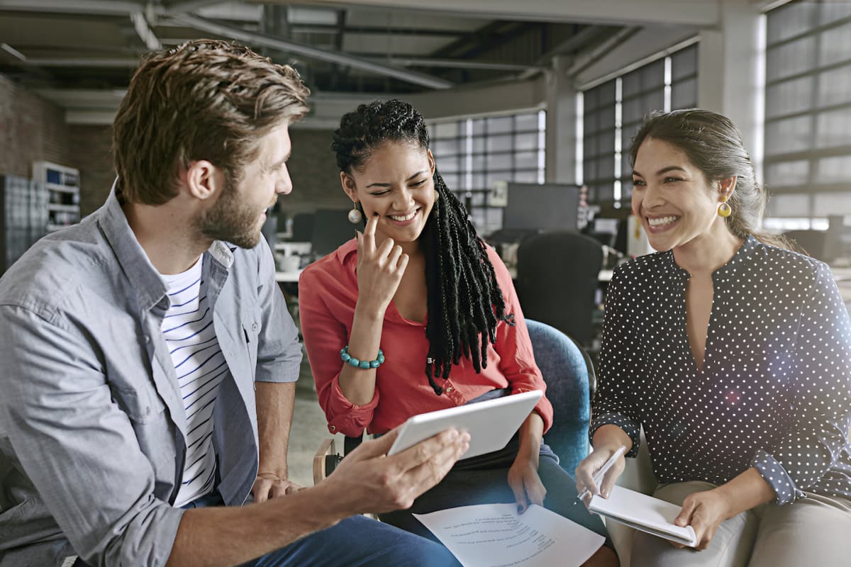 Employees reviewing work on tablet and laughing