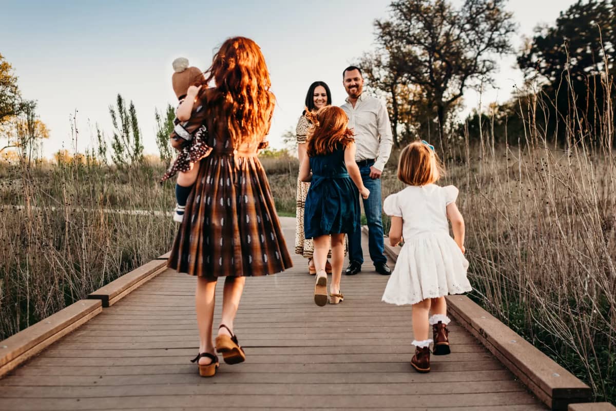 family on dock in formal attire, daughter running towards parents