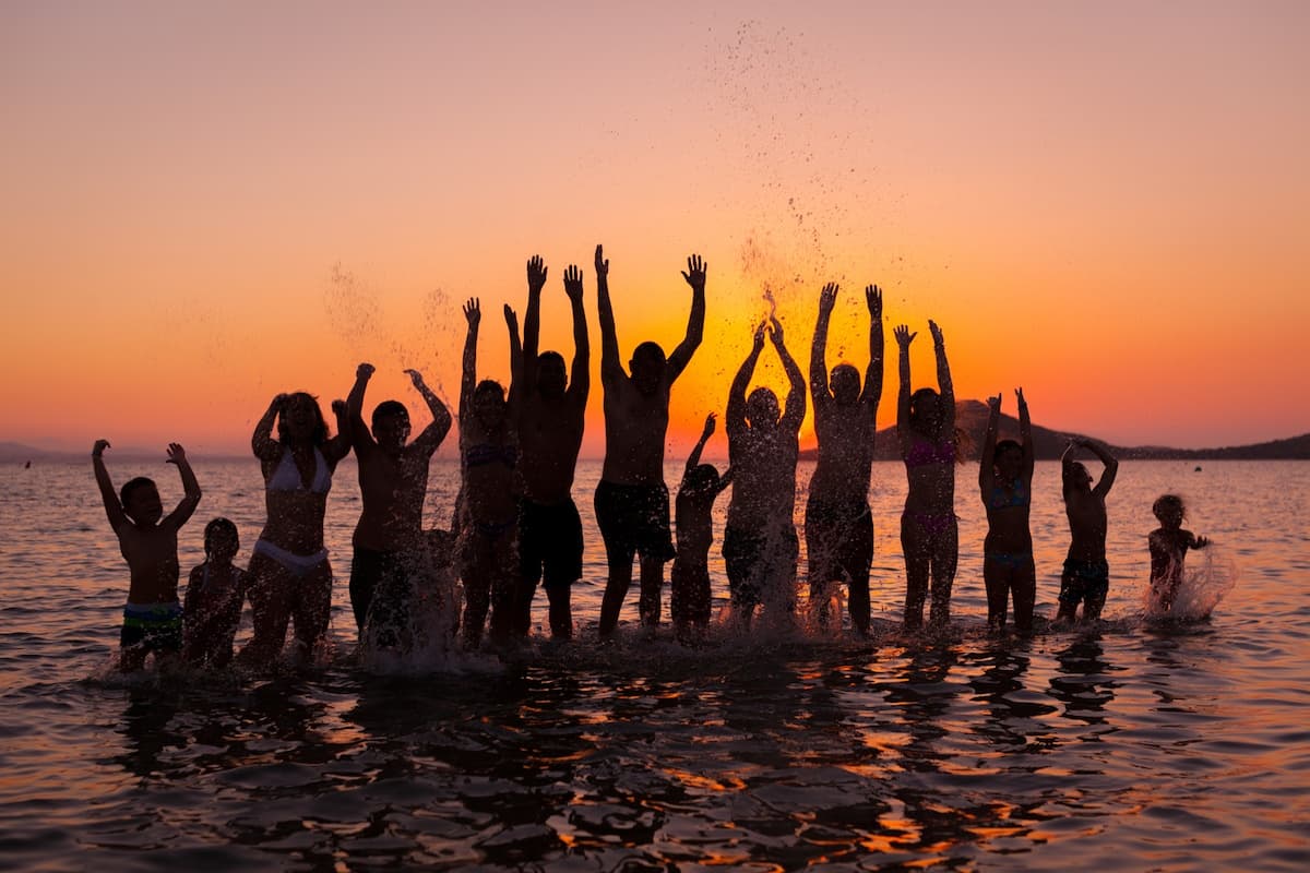 Group of people in water at beach with hands raised