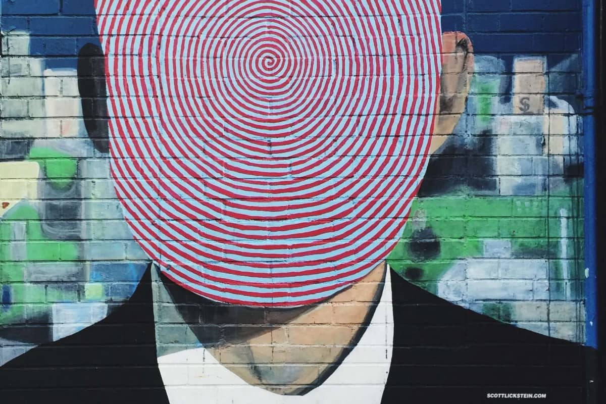 graffiti of man in business suit with red spiral face