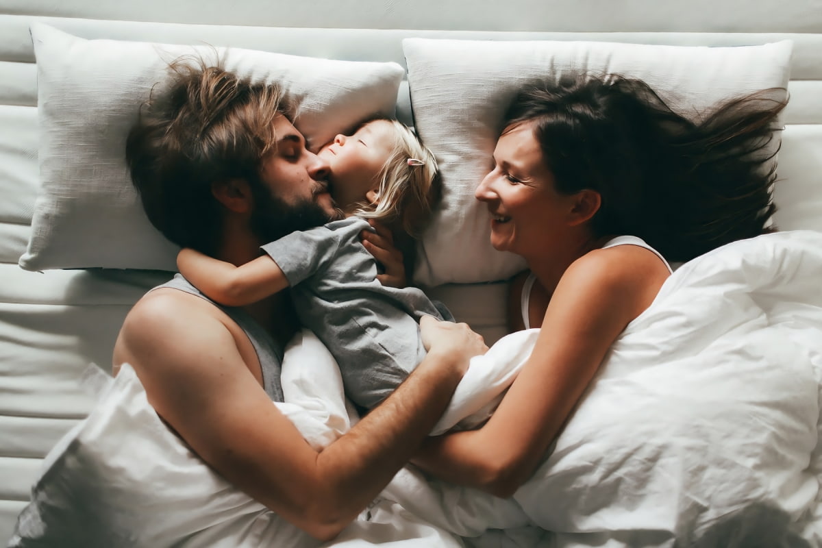 parents with kid in bed