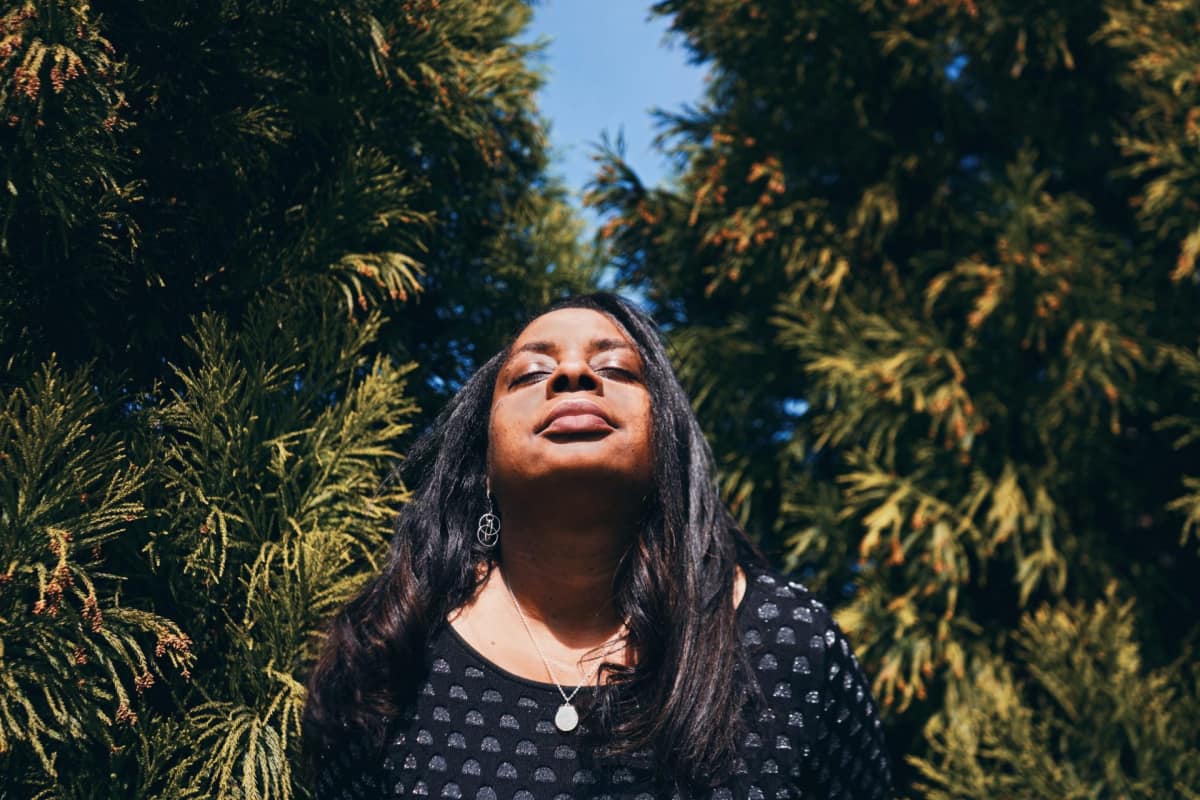 African American woman relaxes in nature, head up, eyes closed