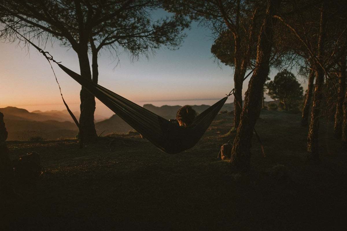 Woman in a hammock in the forest at sunrise