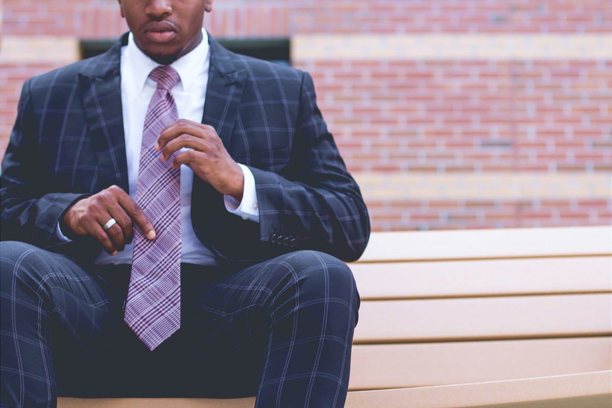 African American man sitting outside fixing his tie