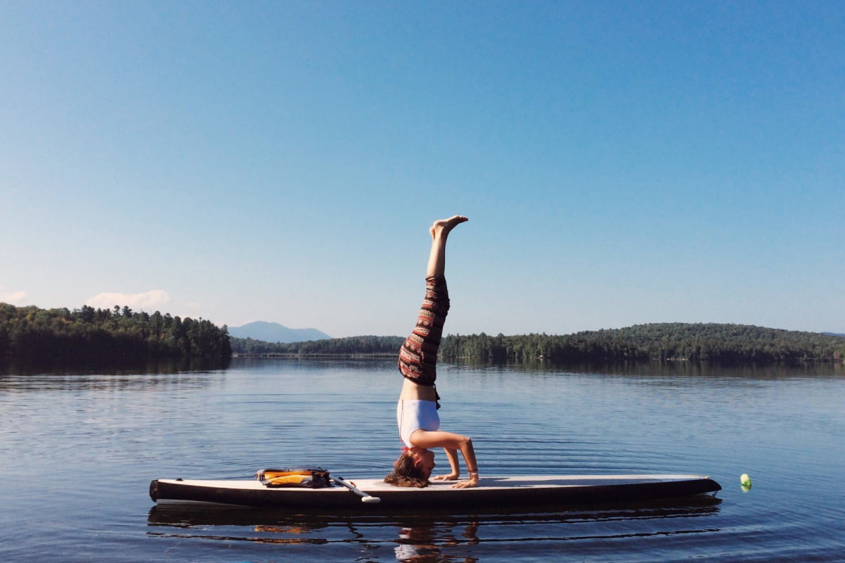 Woman doing yoga on surf board on a lake