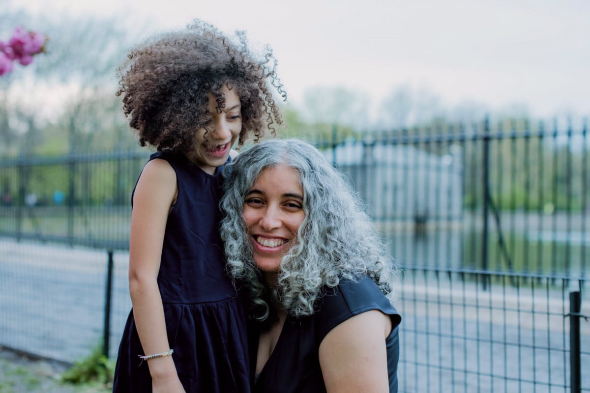 Mother with long gray curly hair and young daughter smiling