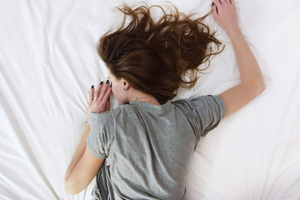 tired woman laying on stomach down on bed