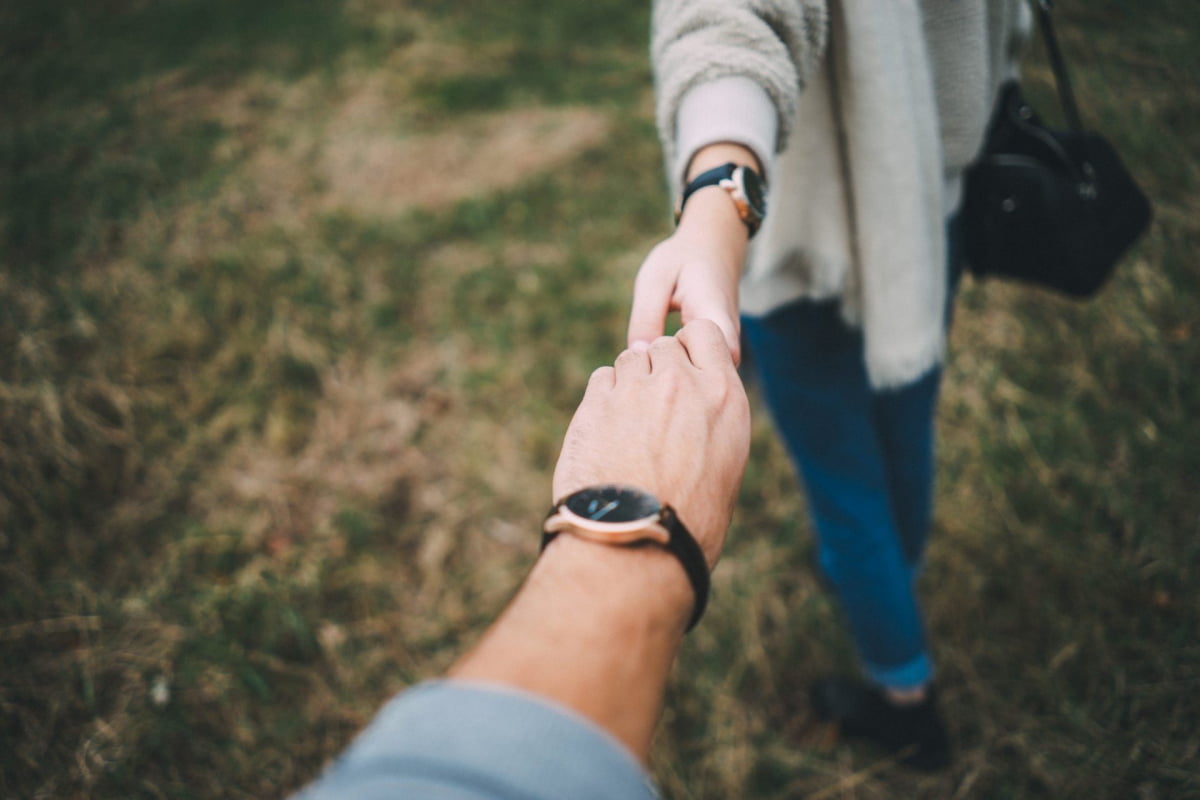 man being lead by woman by the hand